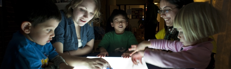two college students, 3 children, playing a game under low light