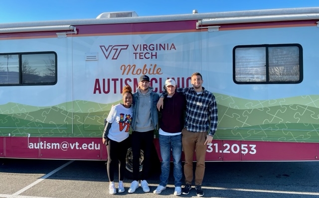 4 undergrad research assistants standing in front of the Mobile Autism Clinic