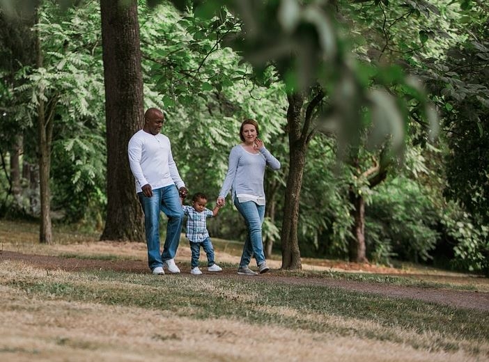 Autism in Motion example Father, young daughter and mother walking through park