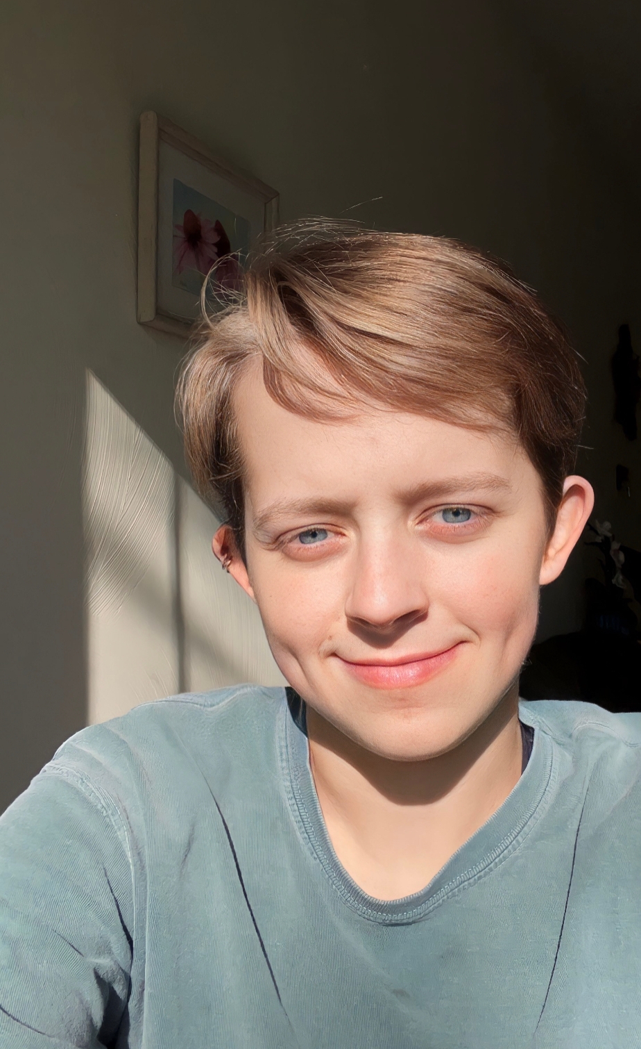 Self-portrait of Claire, who has short blonde hair and is wearing a light gray t-shirt