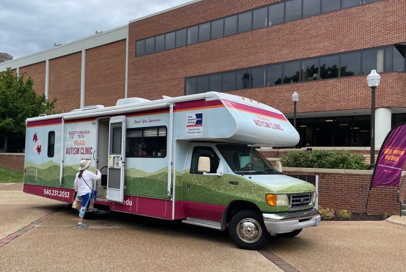 Mobile Autism Clinic RV parked outside of Squires Student Center at VT with an alumni entering